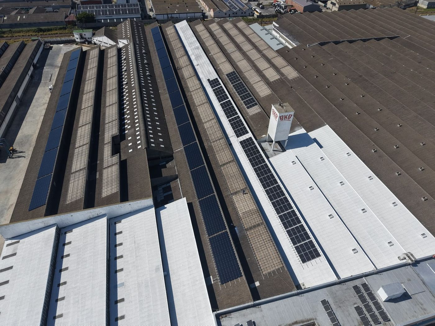 Factory roofs sealed white beside older asbestos cement roofs